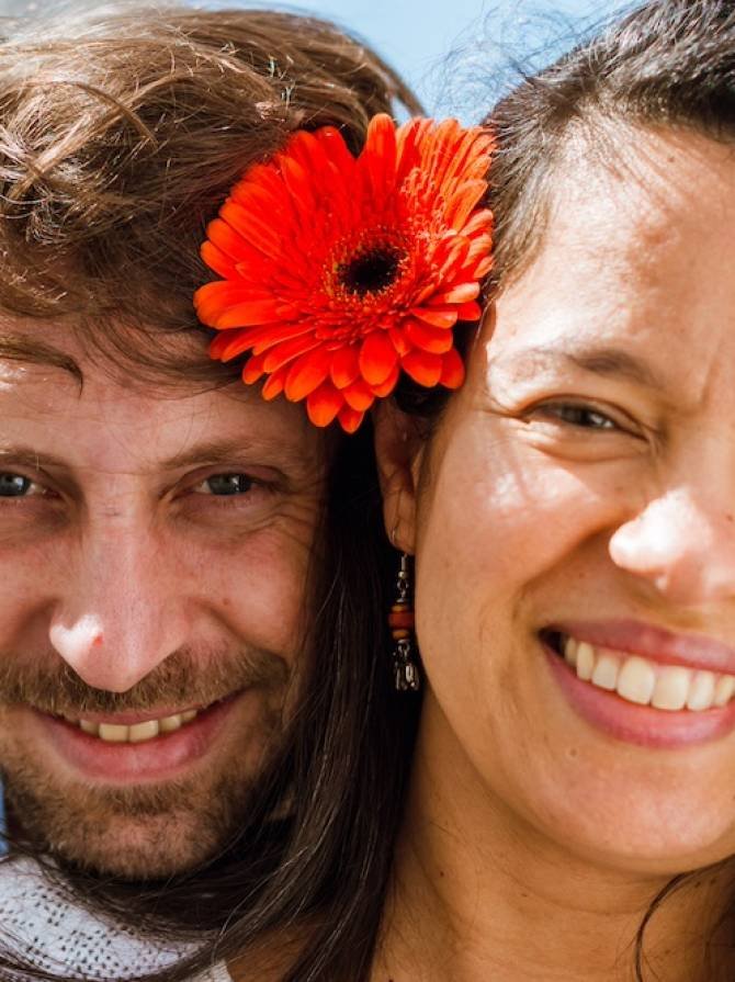 Portrait Of Latin Adult Man And Woman, Looking At The Camera With A Flower In The Ear And Smiling